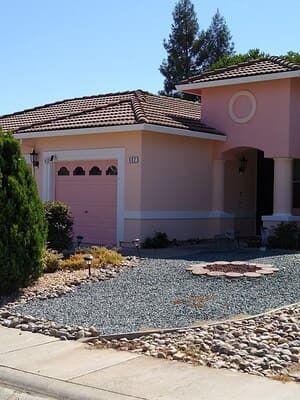 Suburban house with pink stucco exterior, tiled roof, and rock landscaping in front yard
