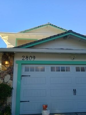 House front with white garage door, teal trim, and address number 2809 under a clear blue sky