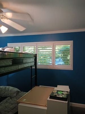 Bedroom with blue walls, bunk bed, dresser, and window with white shutters