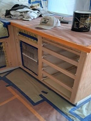 Partially built wooden cabinet with open shelves and a countertop in a workshop