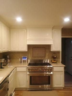 Modern kitchen with cream cabinets, stainless steel stove, and granite countertops under recessed lights