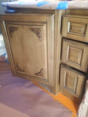 Wooden kitchen cabinet with ornate trim, viewed close up from the floor.
