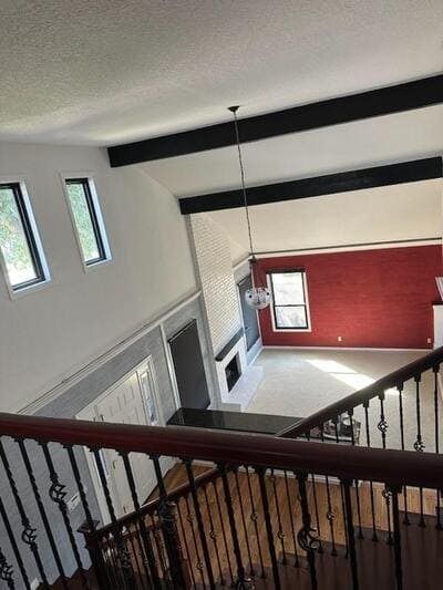 Loft view of a bright room with white walls, dark ceiling beams, red accent wall, and large windows