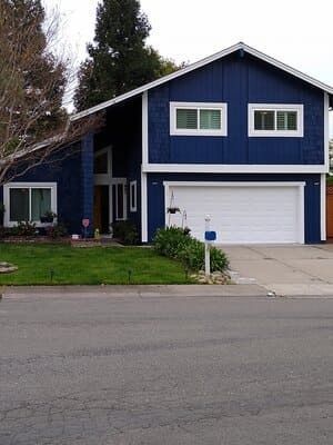 Blue two-story house with white trim and a garage, viewed from the street.