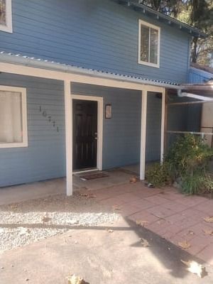Blue house exterior with white porch columns, black front door, and tiled walkway.