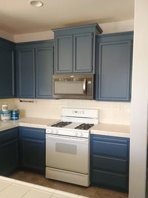 Blue kitchen with white stove, microwave, and cabinets.