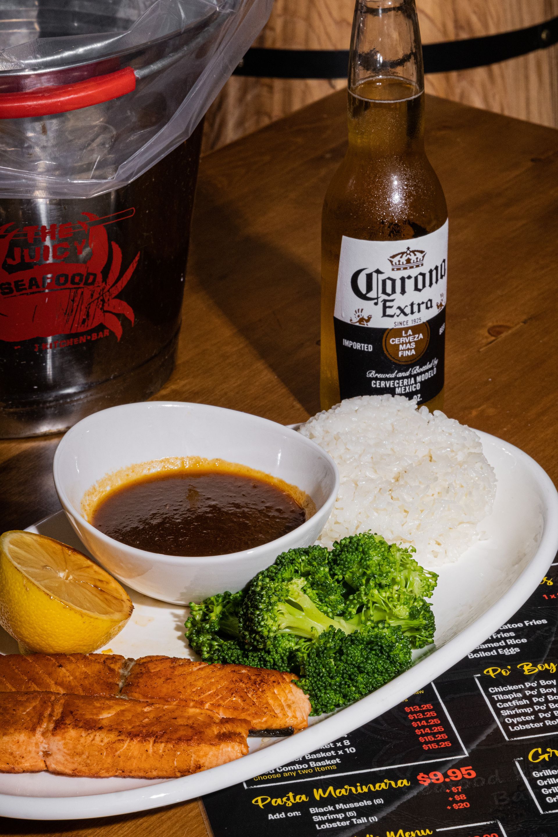 A plate of food and a bottle of corona extra beer on a table.