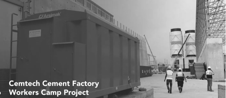 A group of construction workers are walking in front of a large blue container.