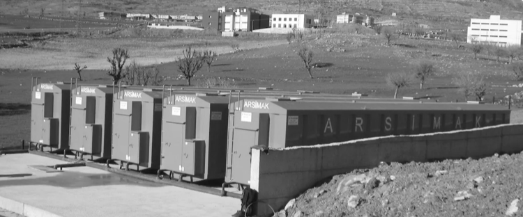 A row of blue portable toilets are lined up in a field