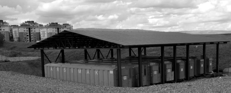 A row of blue containers under a red roof.