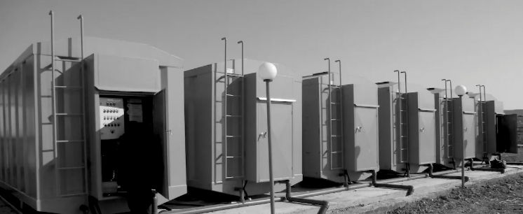 A row of blue containers are lined up in a field.