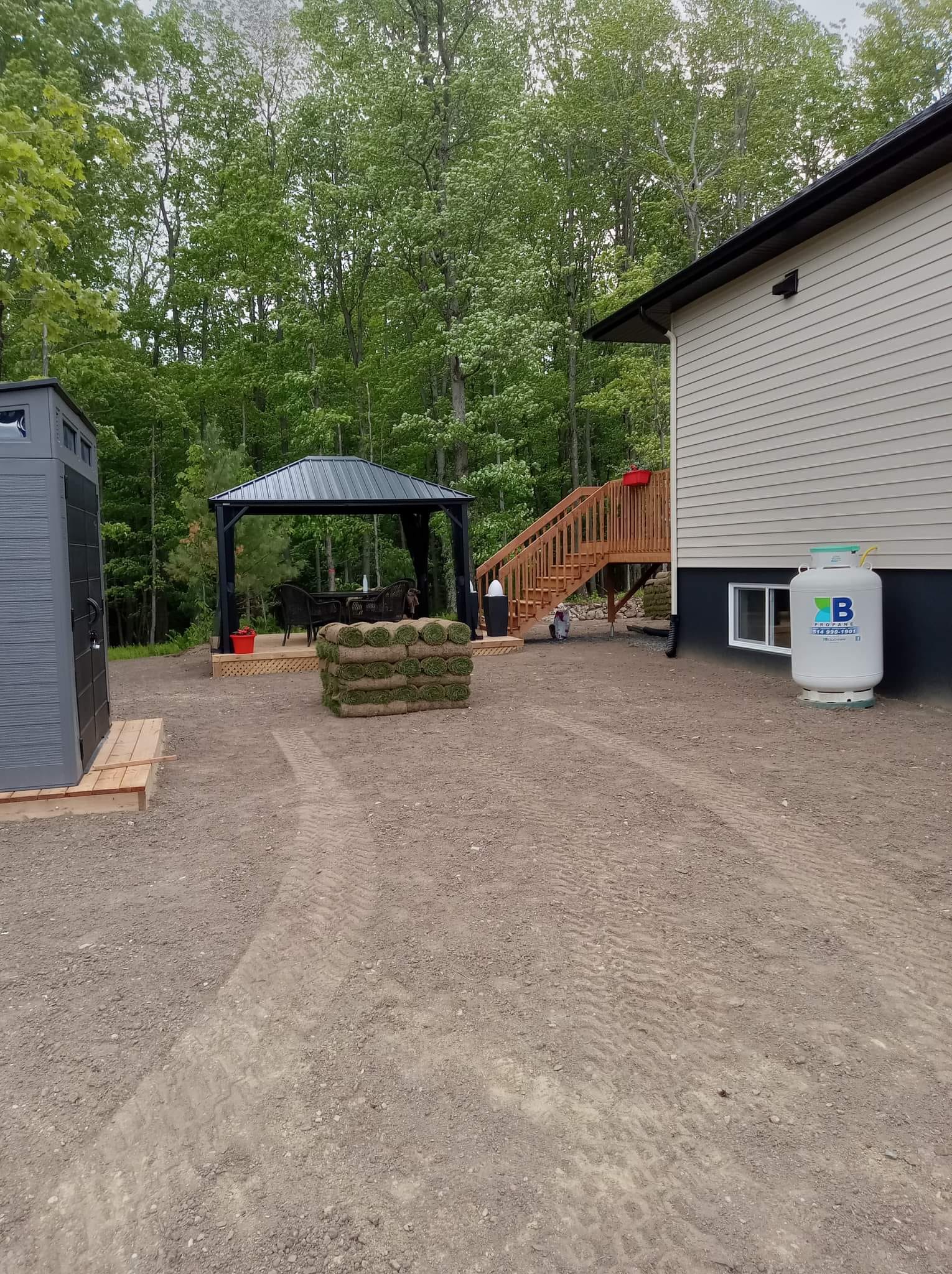 Rouleaux de tourbe empil&eacute;s sur un terrain am&eacute;nag&eacute; pr&egrave;s d'une maison.