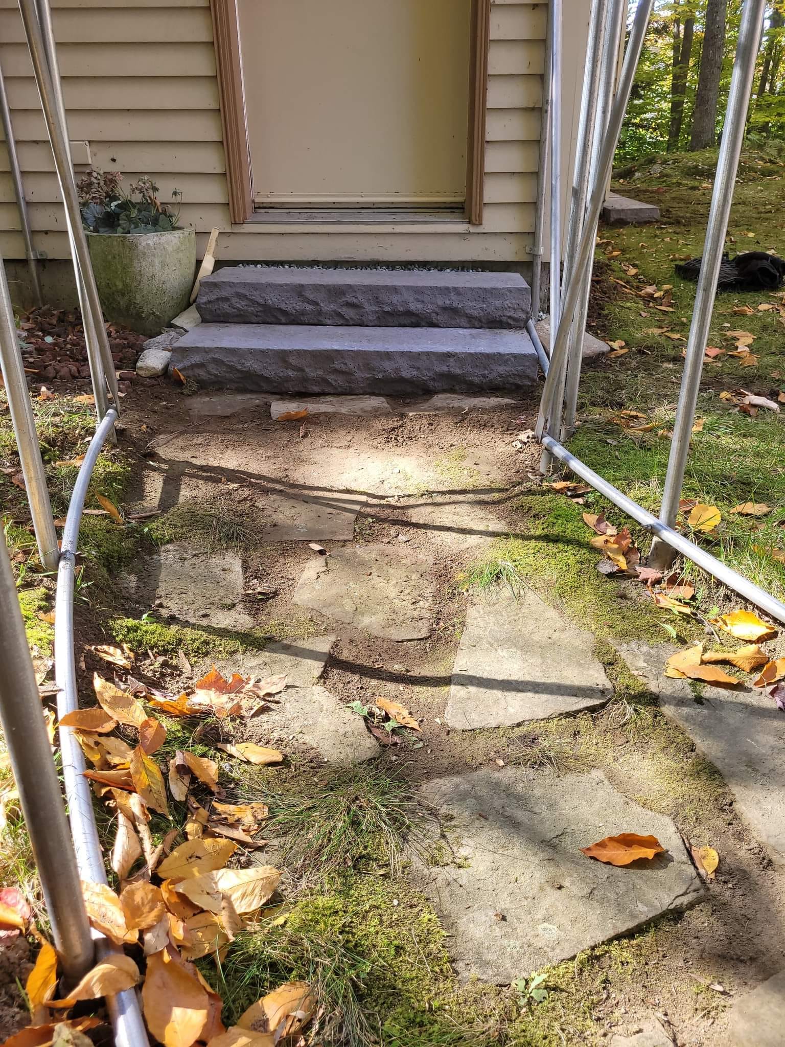 Des marches en pierre mènent à une porte beige, surmontée d'une arche métallique incurvée .
