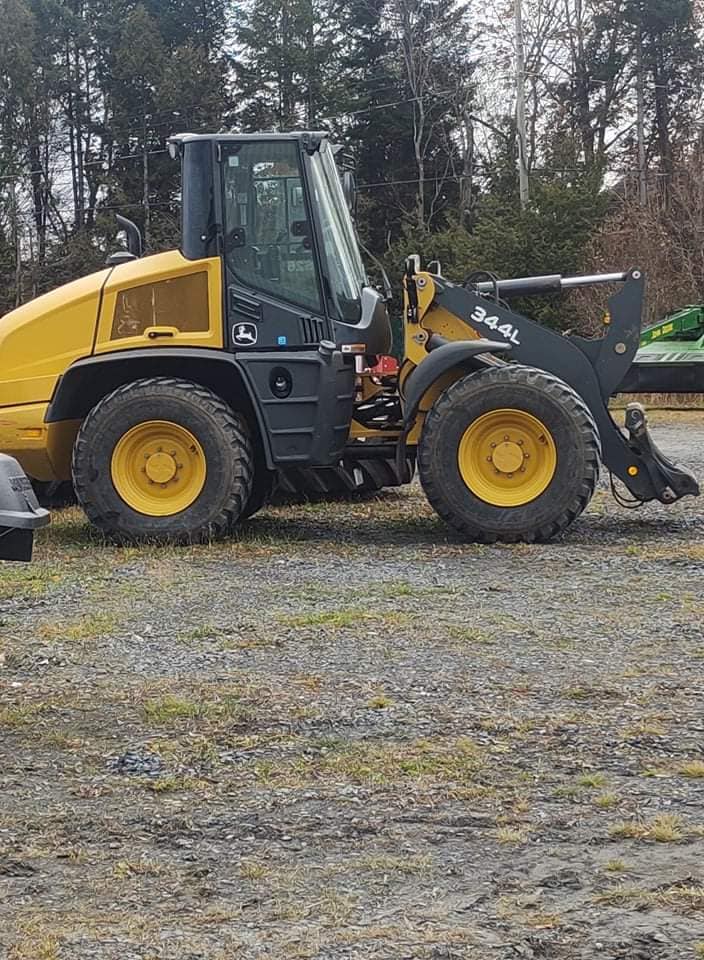 Chargeuse &agrave; roues jaune et noire stationn&eacute;e sur un terrain gravillonn&eacute; avec for&ecirc;t en arri&egrave;re-plan.