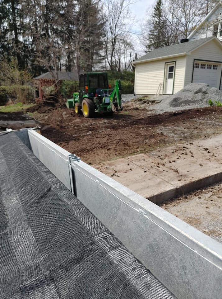 Un tracteur nivelle un terrain résidentiel près d'une maison et d'un garage.