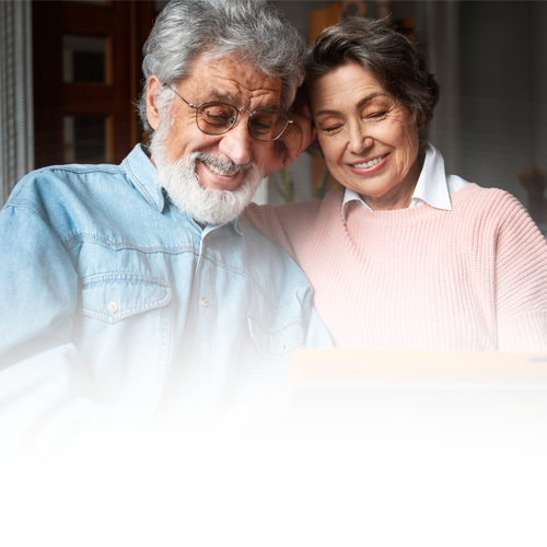 A man and a woman are looking at a laptop together.