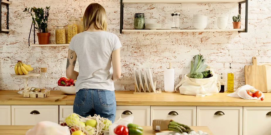 Person standing at a kitchen counter preparing food in a bright, rustic kitchen