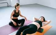 Yoga instructor assisting a person lying on a mat during a stretching session