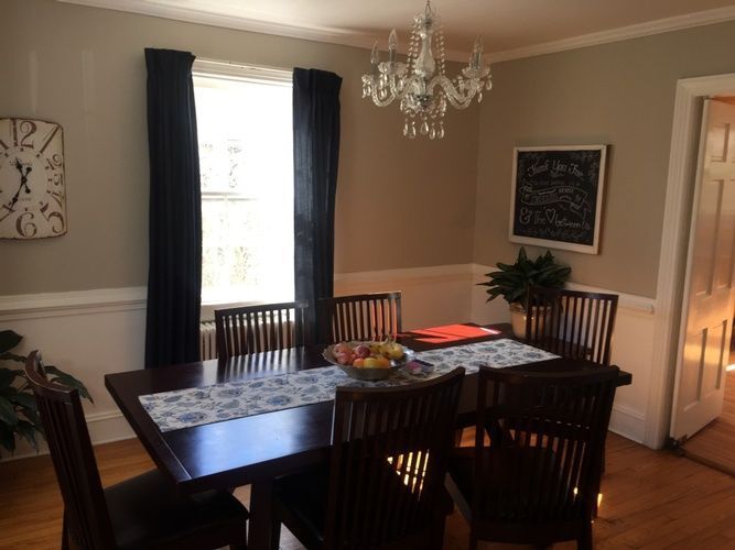 A dining room with a table and chairs and a clock on the wall