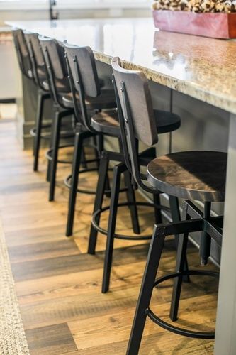 A row of bar stools sitting next to a counter in a kitchen.