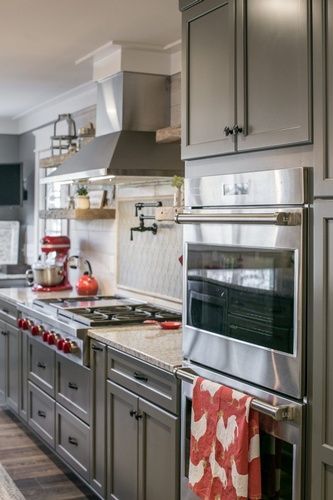 A kitchen with stainless steel appliances and gray cabinets.
