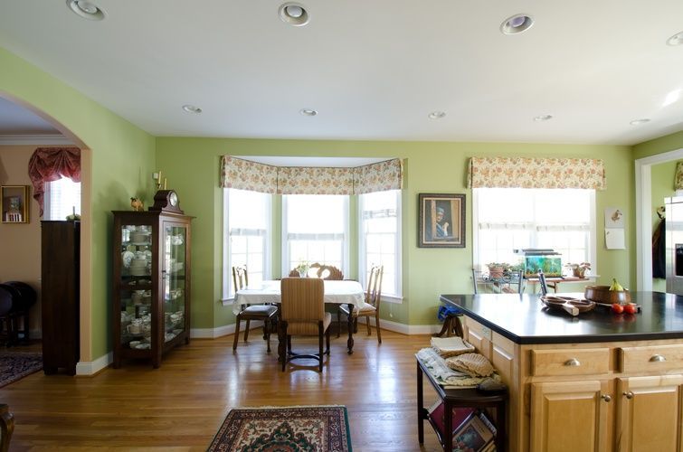 A kitchen and dining room with green walls and hardwood floors