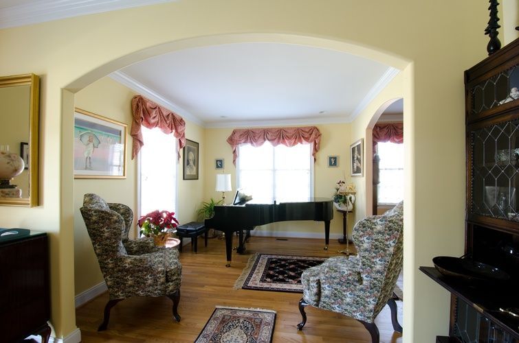 A living room with a piano and two chairs