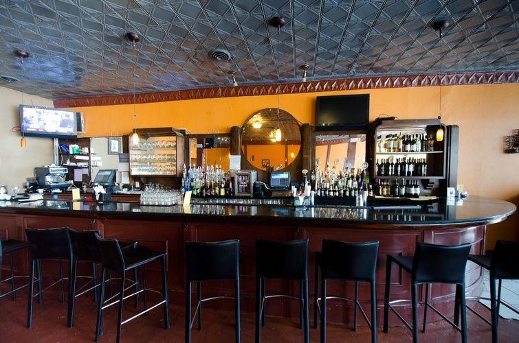 A long bar with stools and a tv on the wall