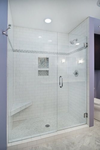 A bathroom with a walk in shower with a glass door and a bench.