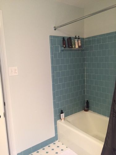 A bathroom with blue tiles and a bathtub.