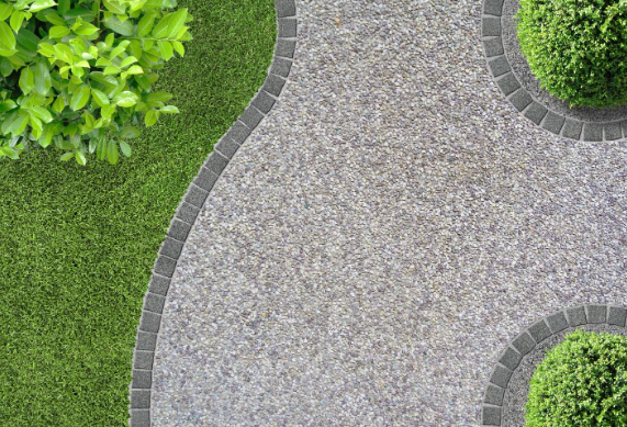 A stone walkway in a park surrounded by grass and bushes.