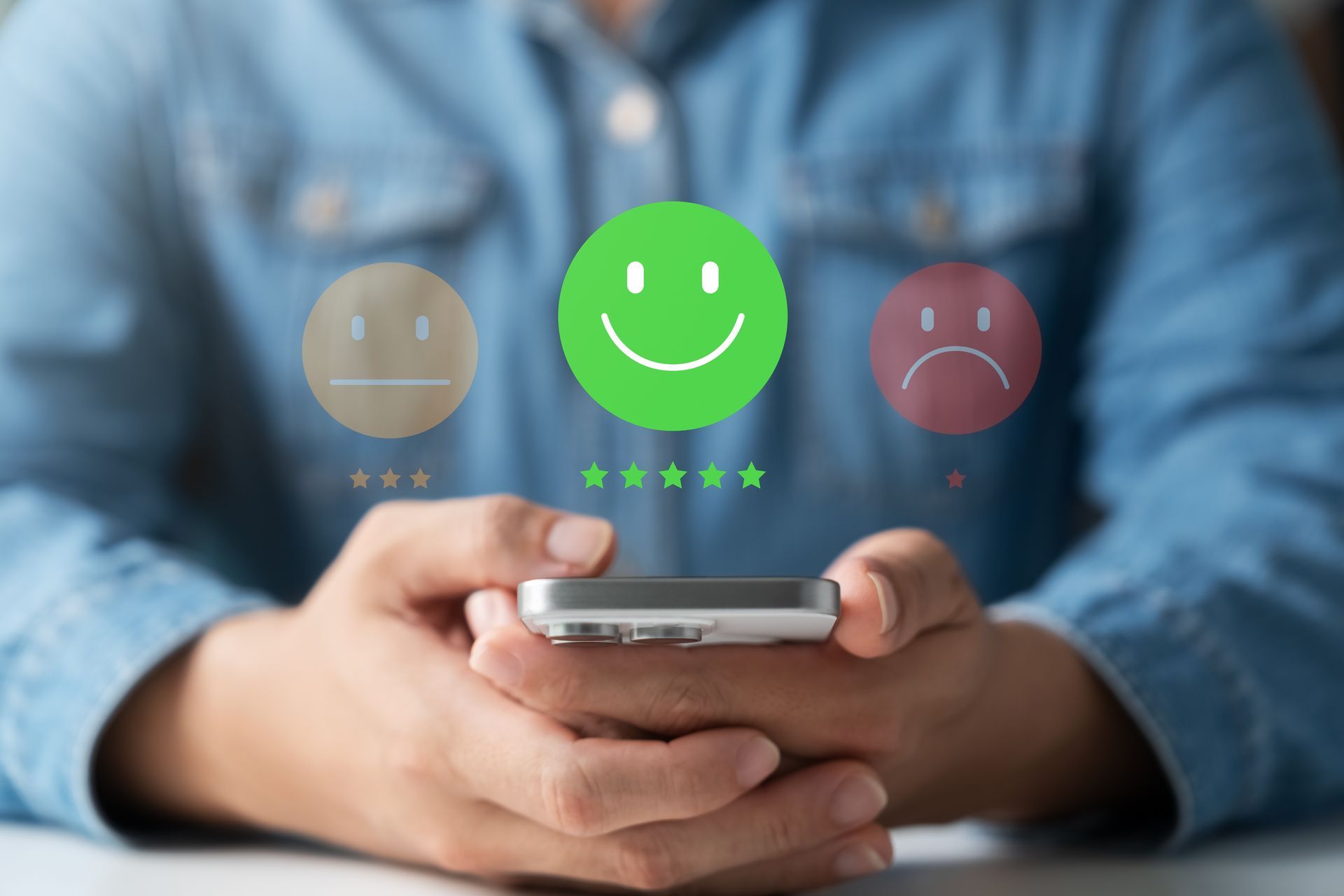 Person holding a smartphone giving a green smiling emoji and five-star rating for customer satisfaction. Person holding a smartphone giving a green smiling emoji and five-star rating for customer satisfaction.