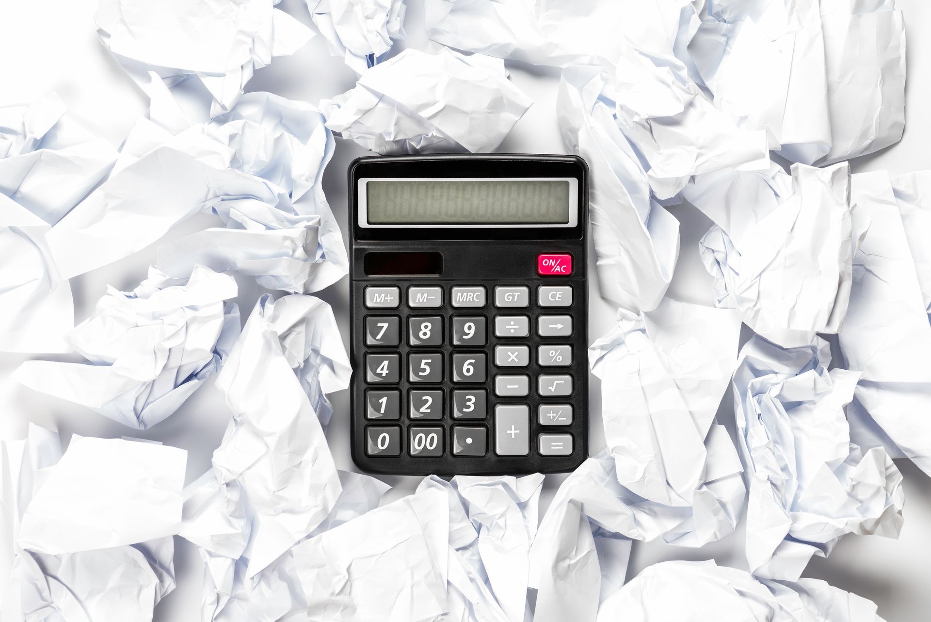 Black calculator surrounded by crumpled white paper. Black calculator surrounded by crumpled white paper.