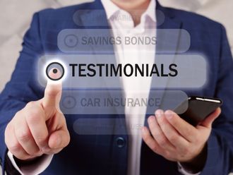 Person in a blue suit pointing to Testimonials on a virtual interface. Holding a phone.