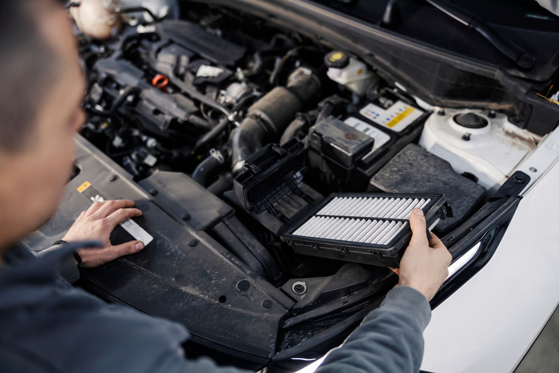Mechanic inspecting a car engine and checking the air filter under the hood Mechanic inspecting a car engine and checking the air filter under the hood