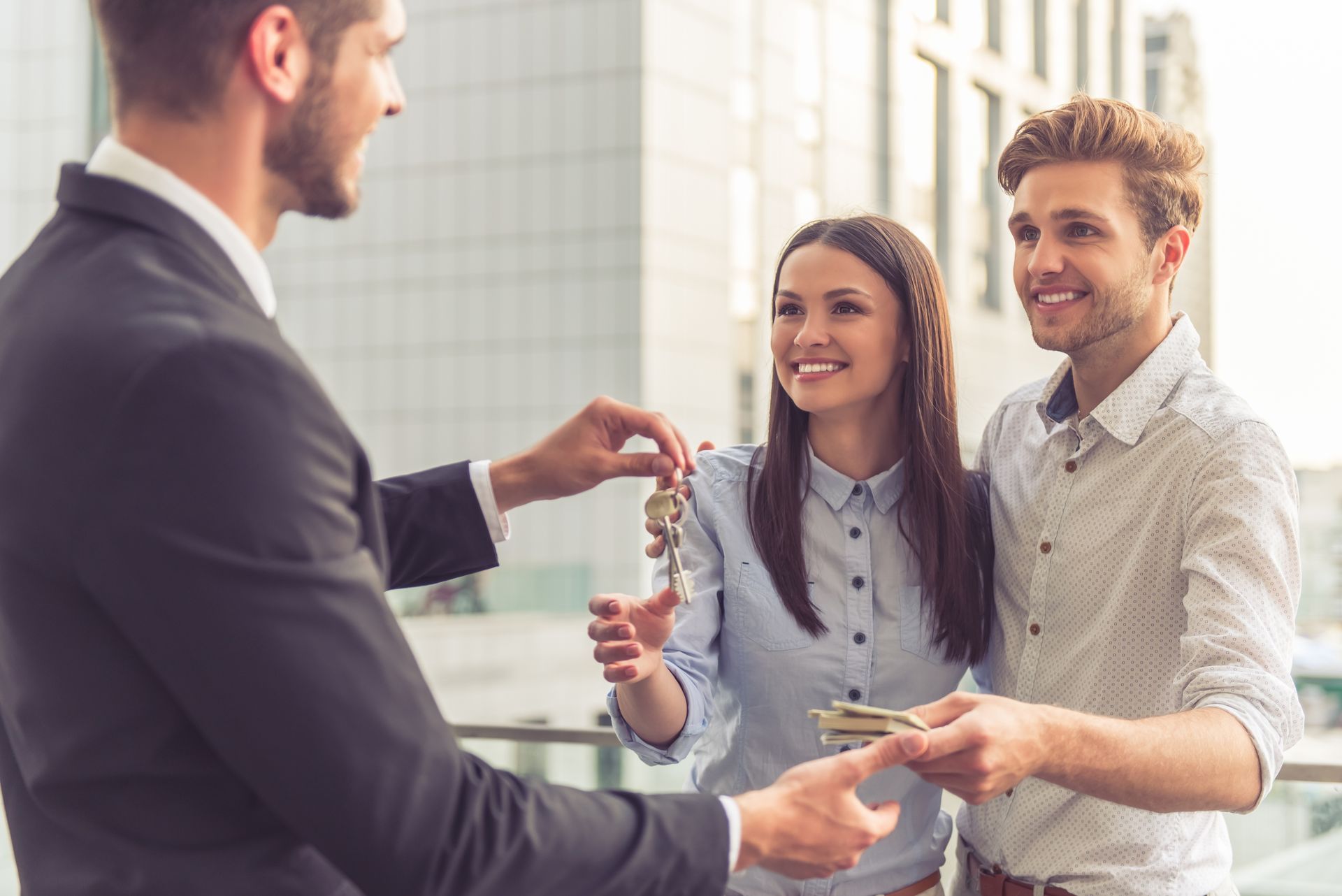 Three people smiling and shaking hands in a bright office meeting area
