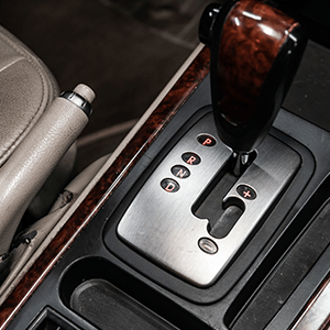 Close-up of a car’s automatic gear shift with wood trim and silver console accents
