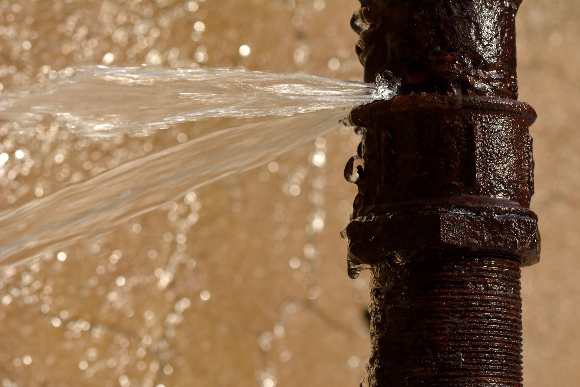 A rusty burst pipe squirting water at high pressure A rusty burst pipe squirting water at high pressure