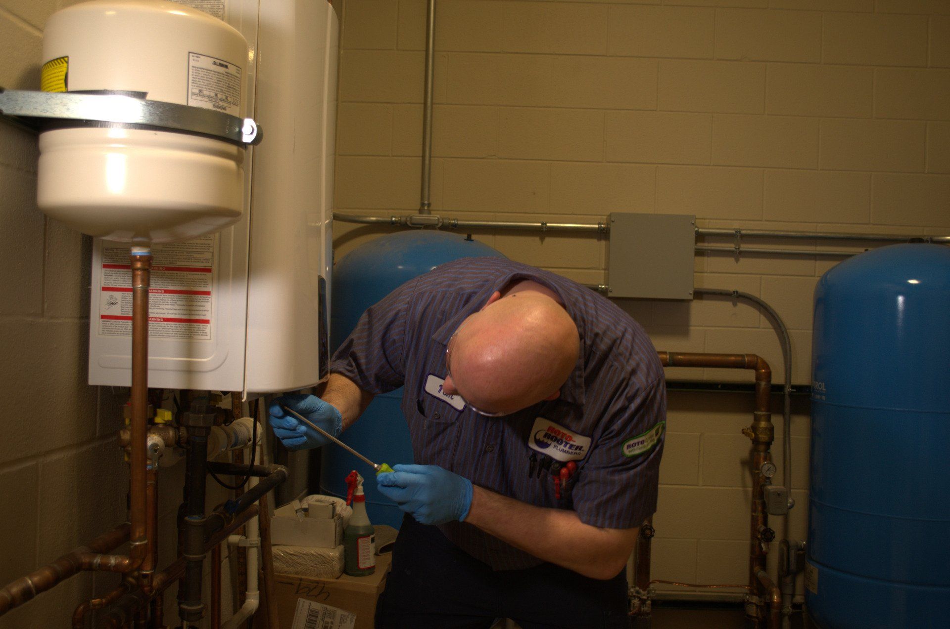 A man is working on a water heater in a basement.