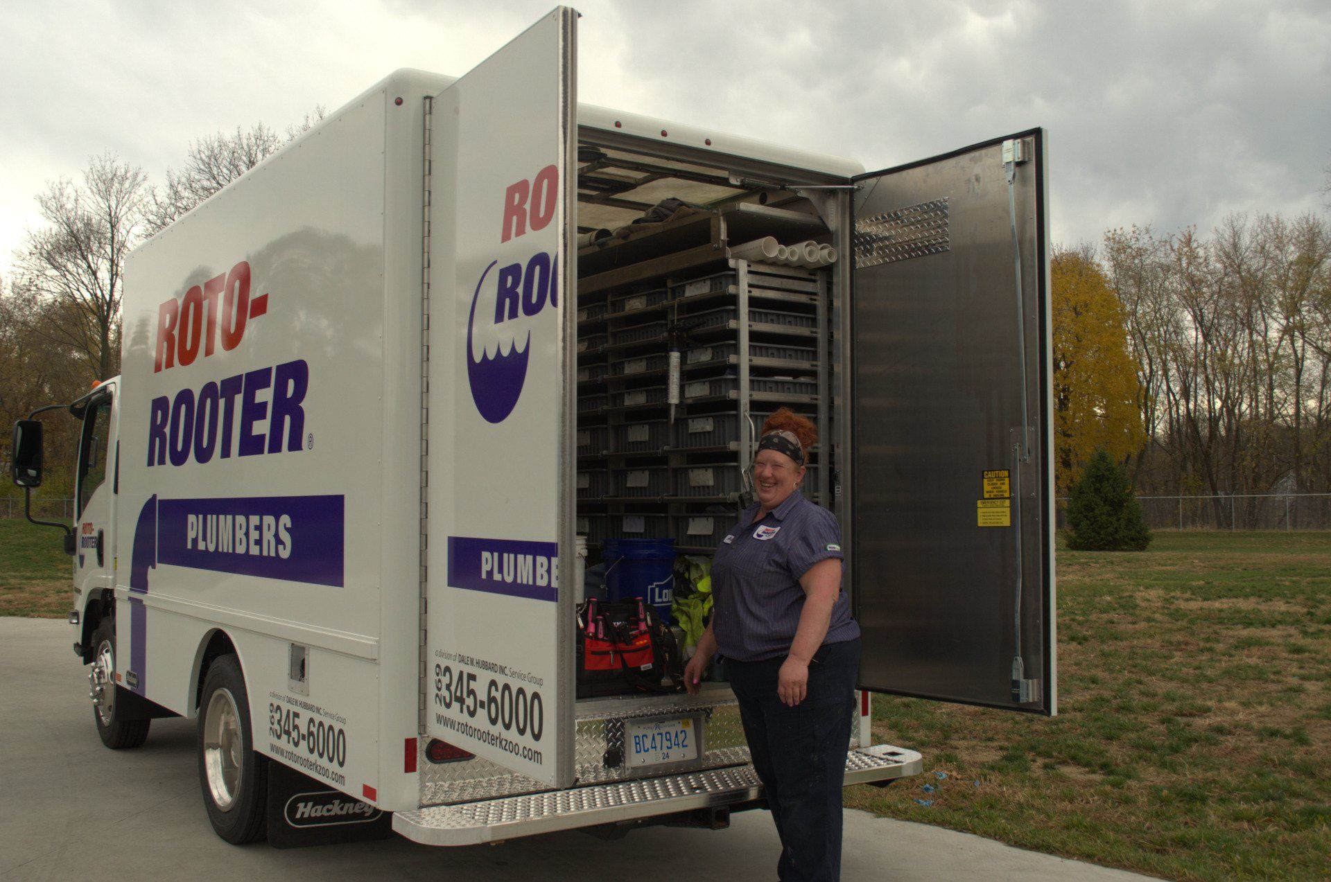 A plumber is standing in front of a roto-rooter truck