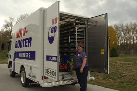 A plumber is standing in front of a rooter truck