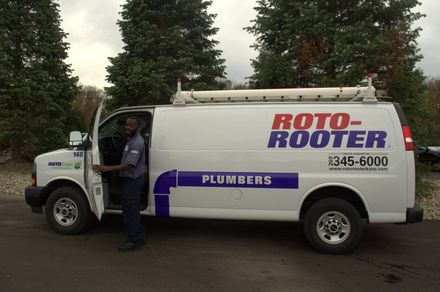 A man is getting out of a roto-rooter van.