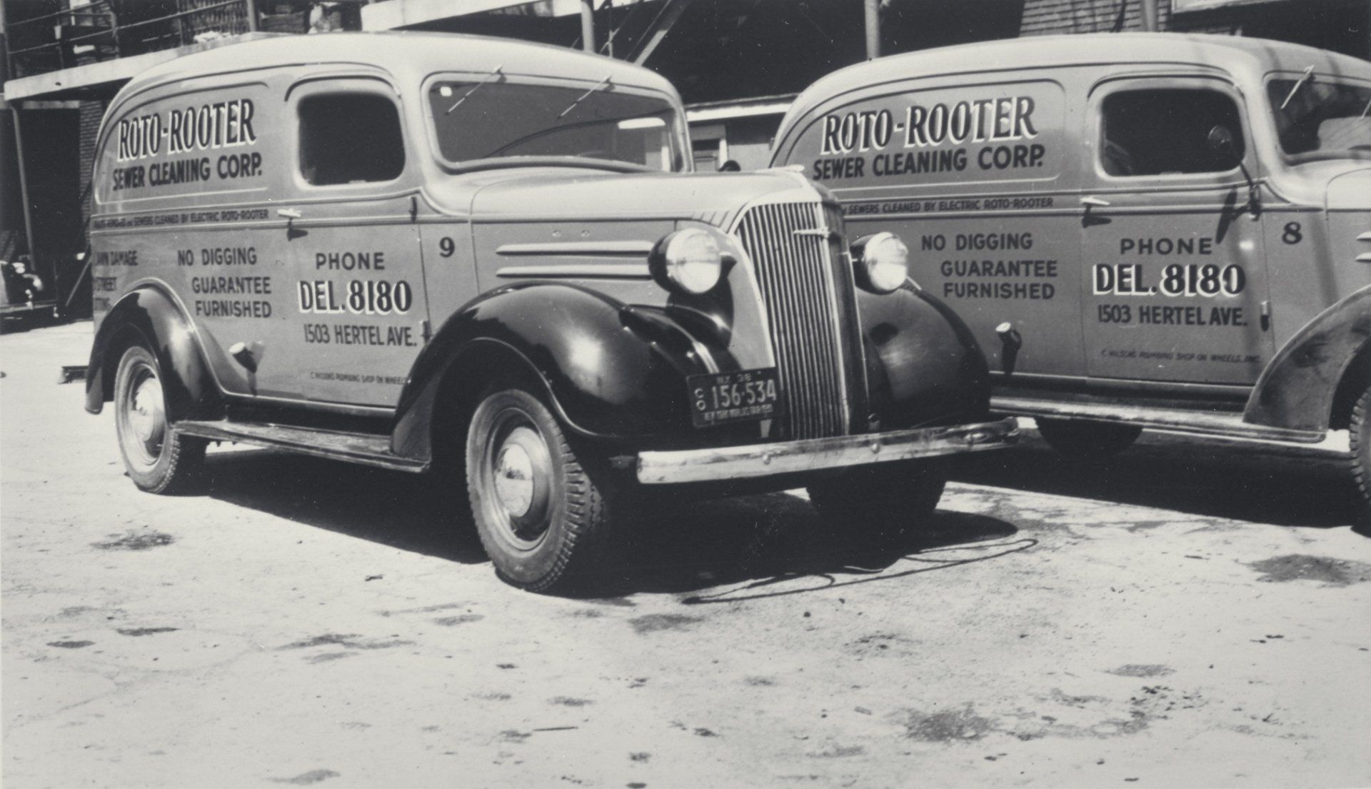 A black and white photo of two old rooter trucks