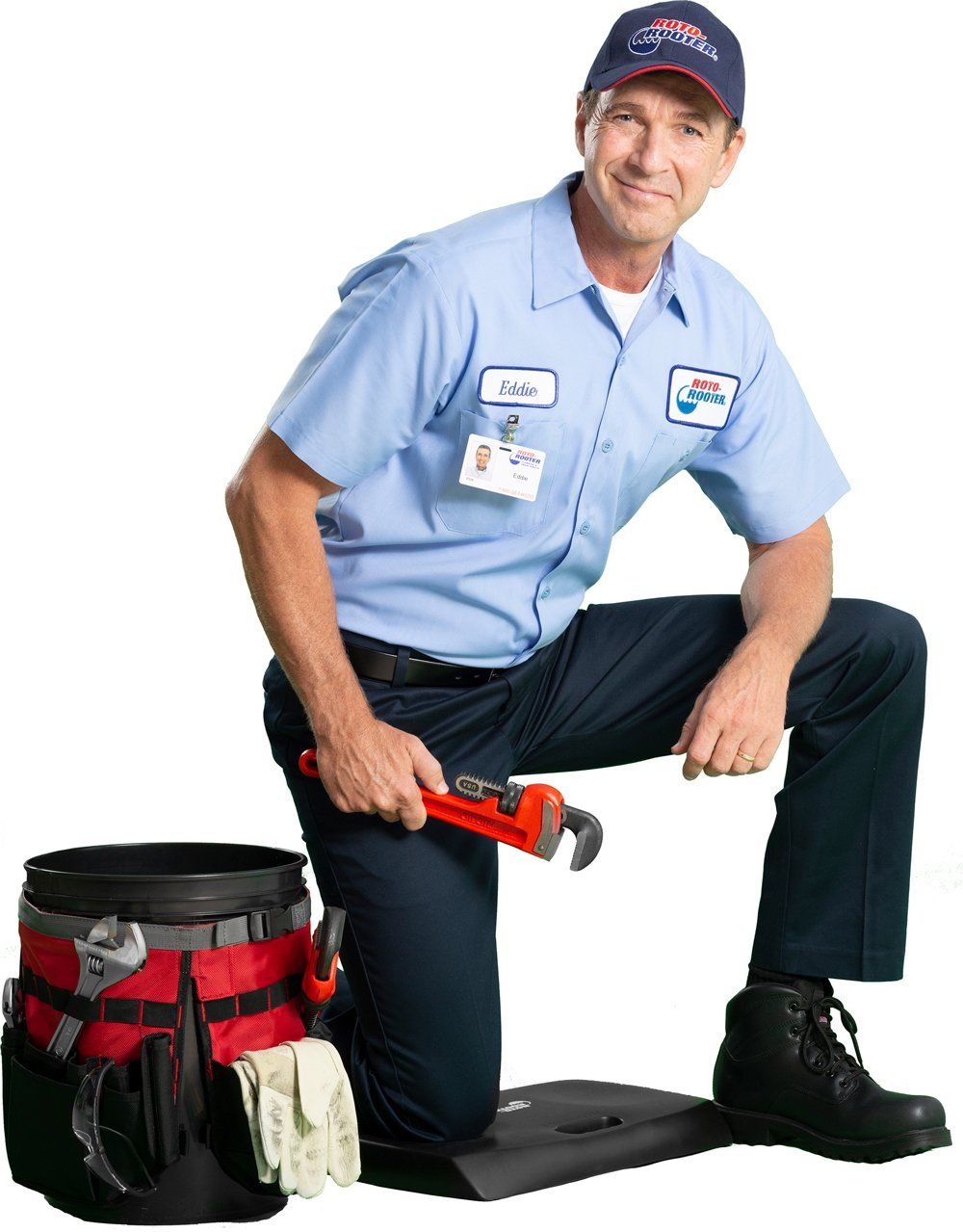 A man in a blue shirt is kneeling down holding a wrench.