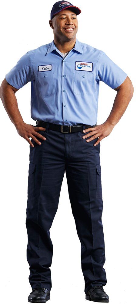 A man in a blue shirt and black pants is standing with his hands on his hips.