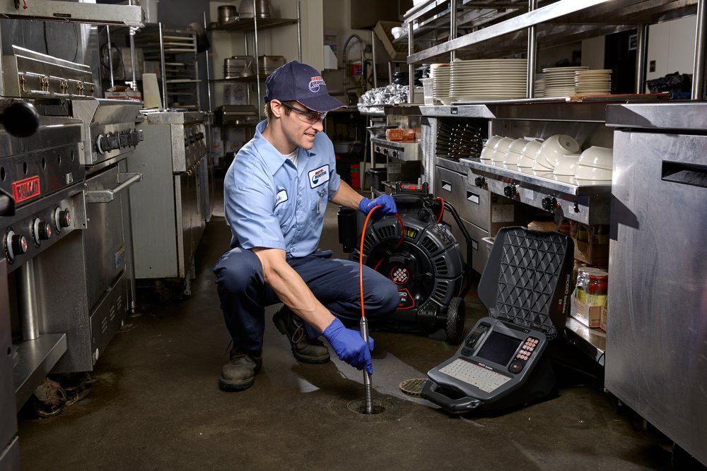 A man is kneeling down in a kitchen with a camera.