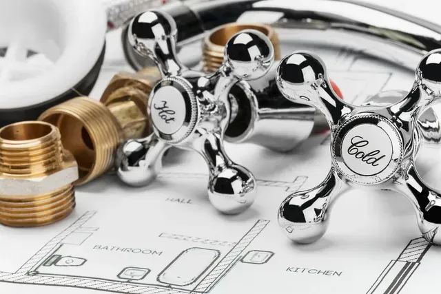 Some plumbing parts on a blueprint: hot/cold faucet handles, pipes, and connectors arranged neatly Some plumbing parts on a blueprint: hot/cold faucet handles, pipes, and connectors arranged neatly