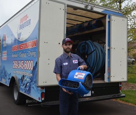 A man is holding a blue fan in front of a carpet restoration truck