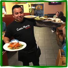 a man wearing a casa maria shirt is holding plates of food