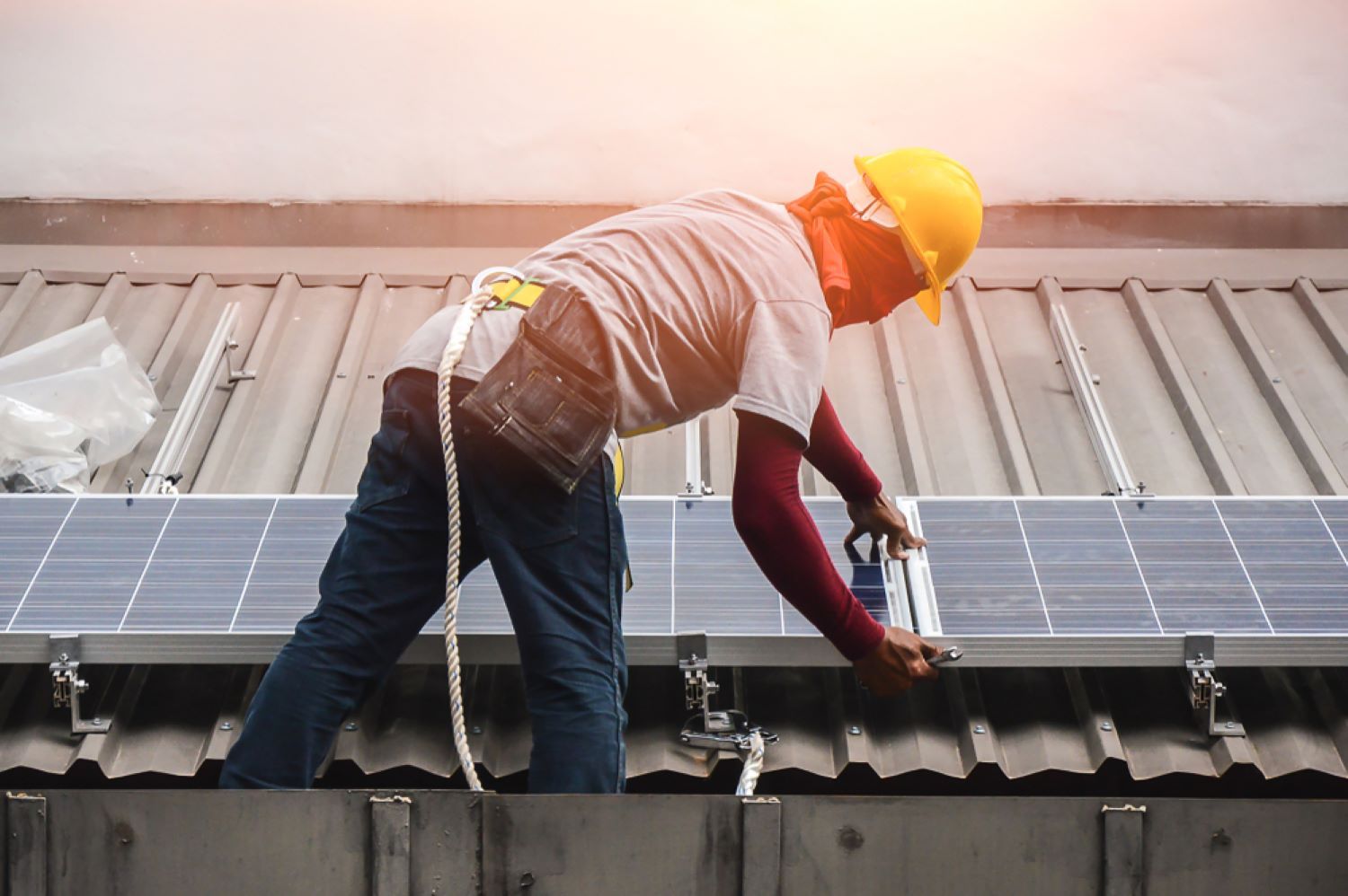 A Man Is Installing Solar Panels on The Roof of A Building — Coffs Coast Plumbing in Korora, NSW